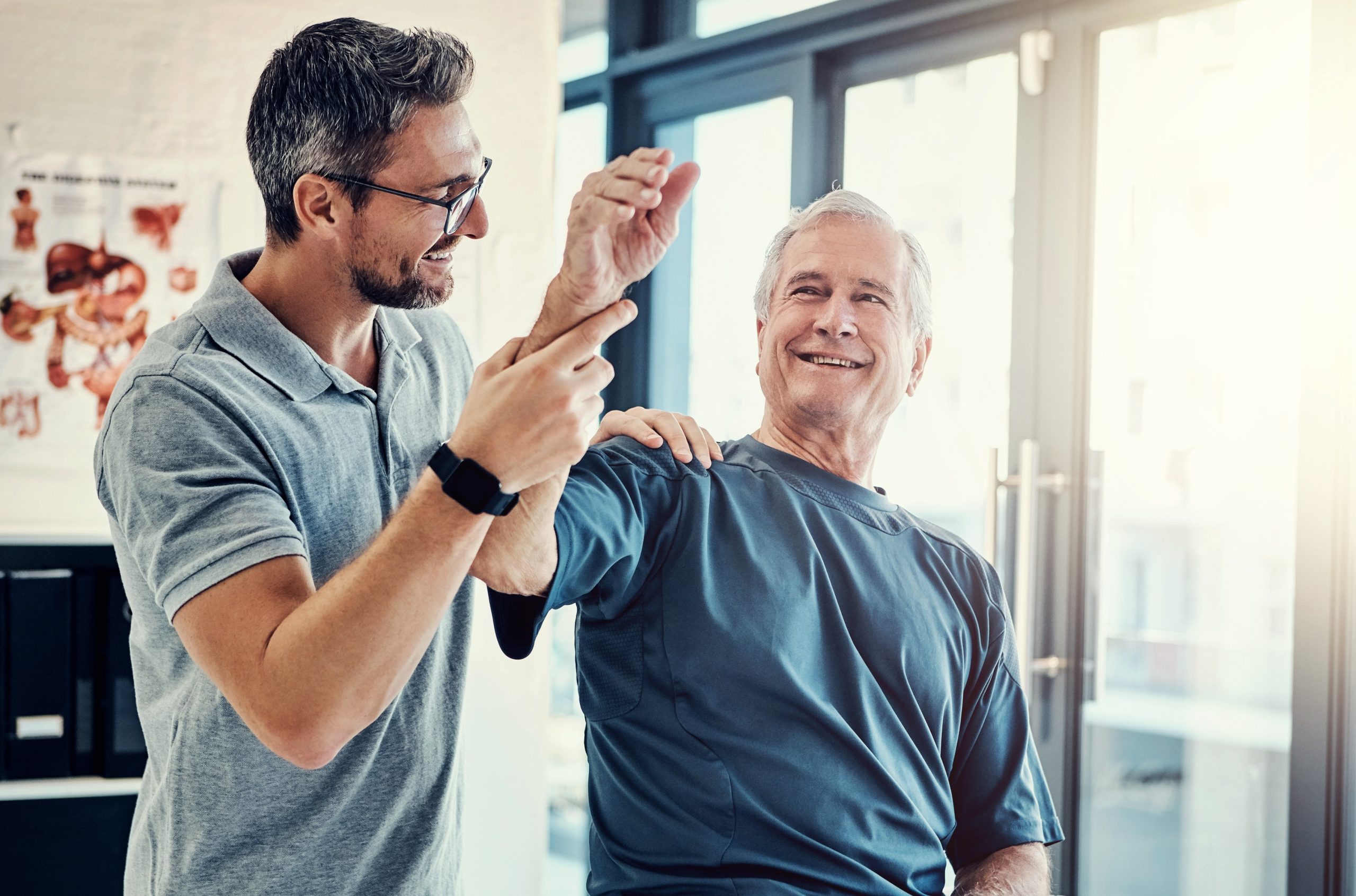 Sports medicine clinician examining older male patient's arm and shoulder in clinical setting